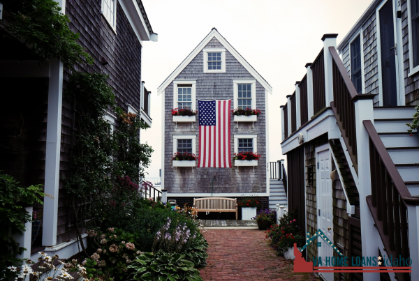 Tall and skinny grey house with an american flag hung on the front of it.